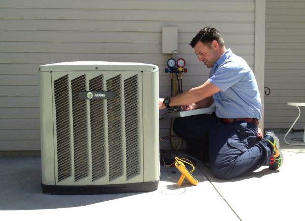 An Atlas Trillo technician repairs an outdoor AC unit at a home in San Jose, CA, using gauges and a multimeter, while kneeling beside the equipment.